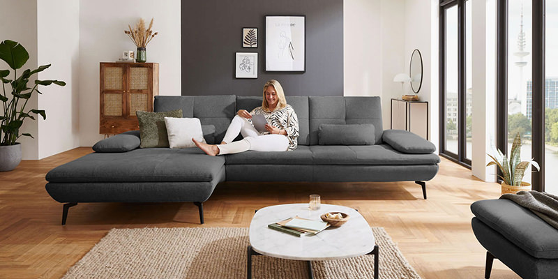 anthrazit-sofa-elenora-auf-juteteppich-umgebung-mit-warmen-toenen-und-holzdetails