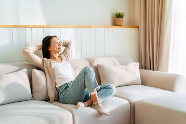 sorgenfreie-frau-sitzt-entspannt-auf-einer-hellen-couch